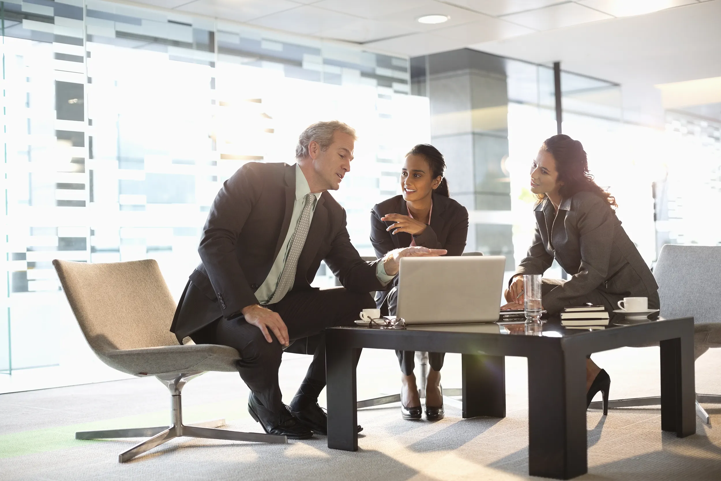 A man and two women discussing a business plan in front of a laptop.