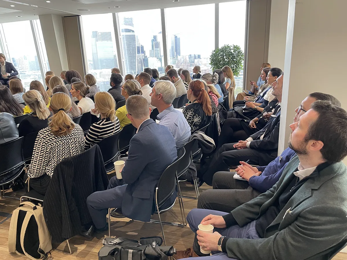 Image of An engaged audience listens, as the City is seen in the background