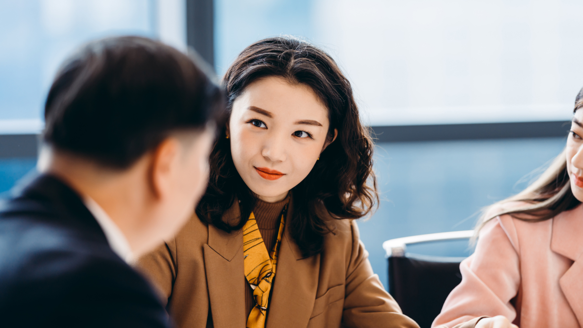 Businesswoman sitting at a table listening to her colleague