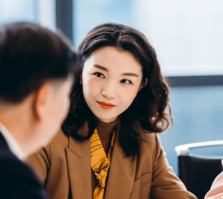 Businesswoman sitting at a table listening to her colleague
