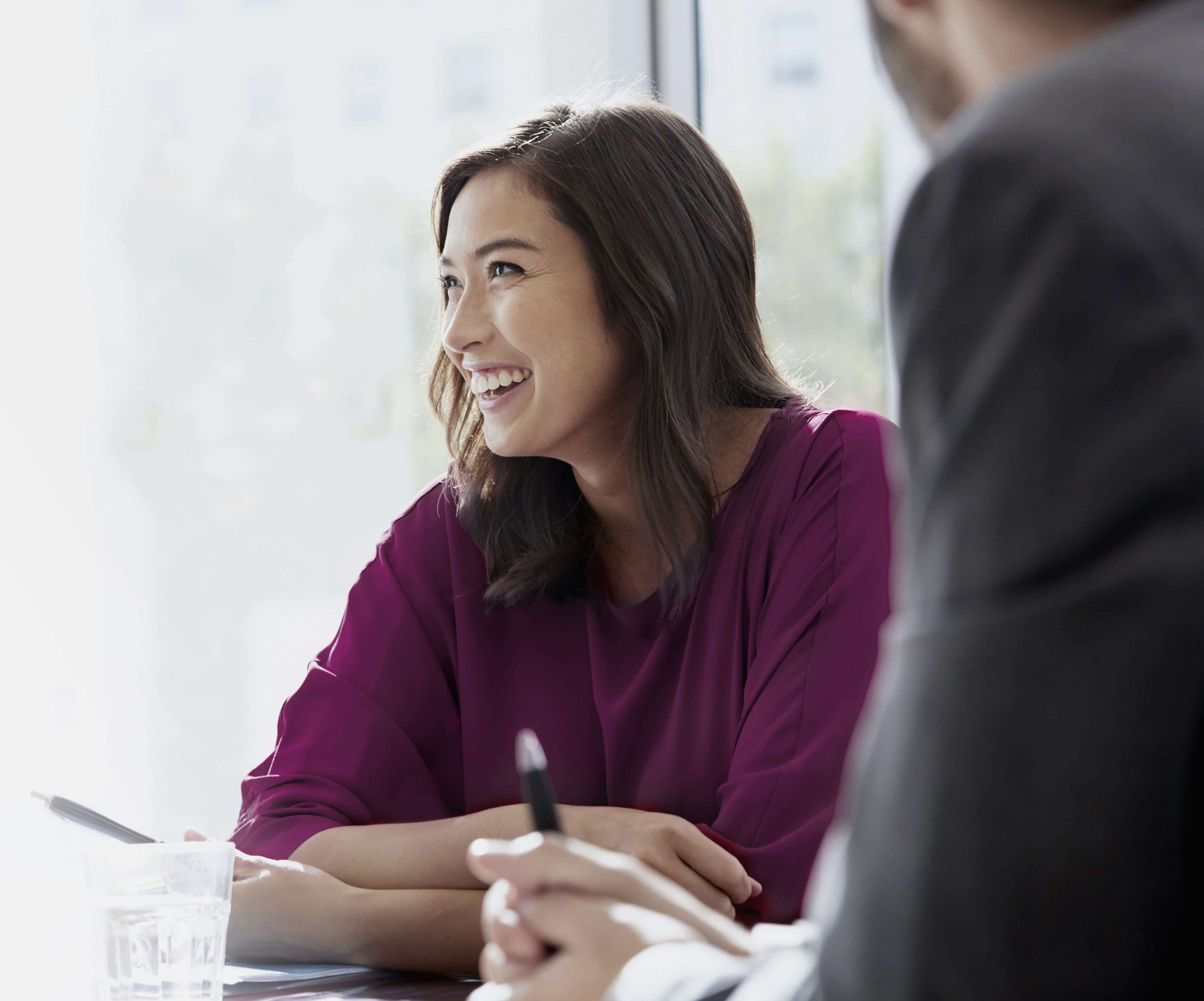 A businesswoman smiles, sitting next to her colleague