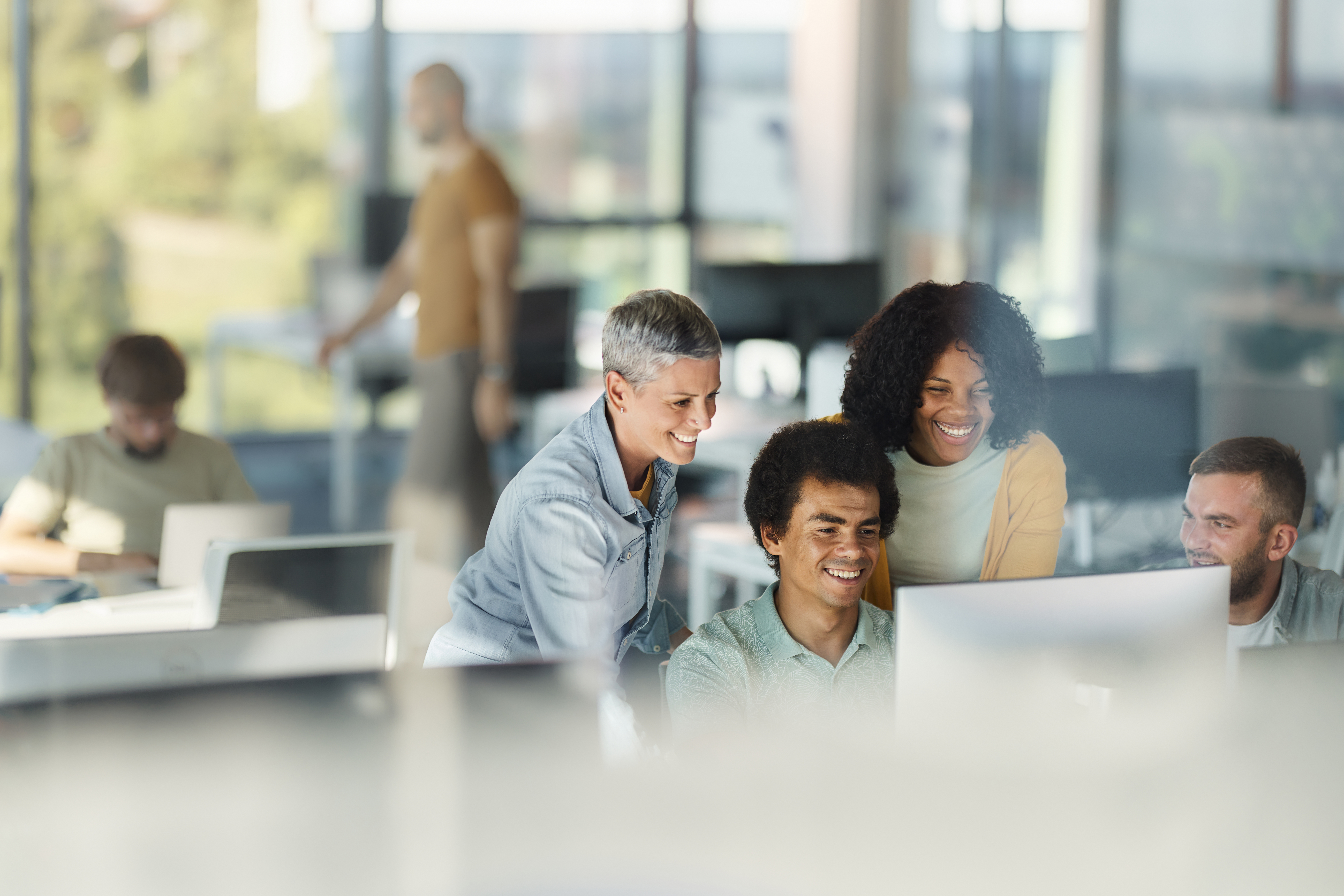 Group of people talking and looking at a computer