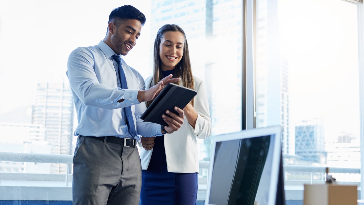Two young business colleagues smiling and looking at information on a tablet