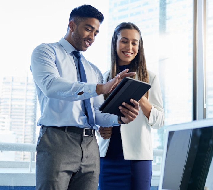 Two young business colleagues smiling and looking at information on a tablet