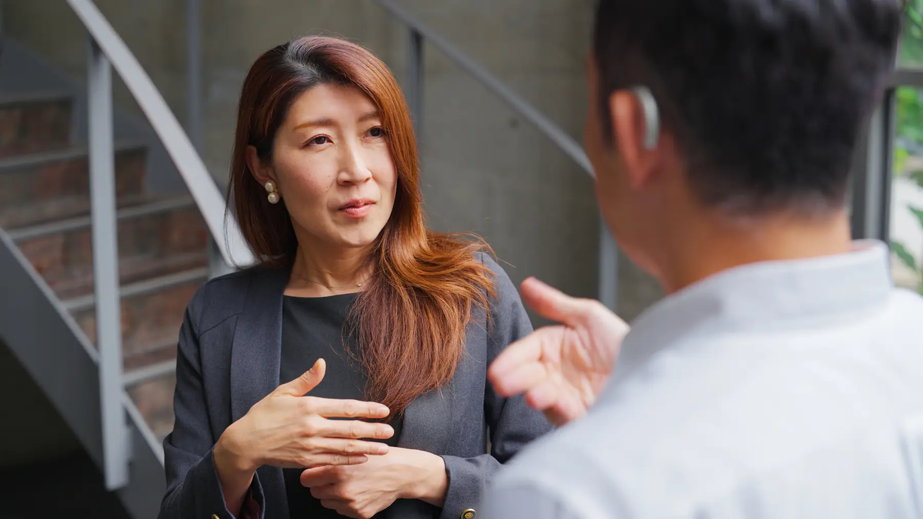 man with hearing aid discussing with coworker