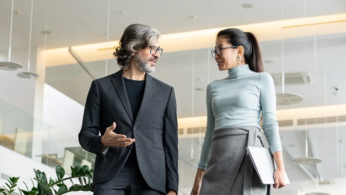 Corporate man and woman walking down steps in office and talking