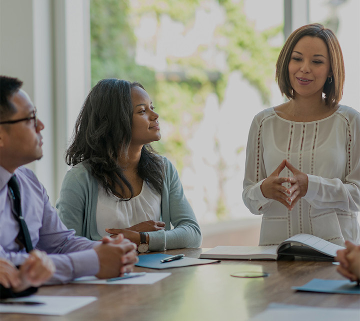 A group of young business professionals attending a presentation in a board room-SQUARE
