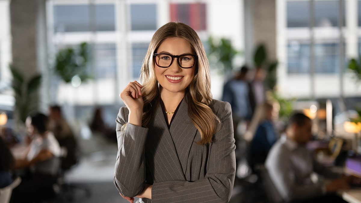 Smiling business woman standing in front of busy and efficient office cubicles