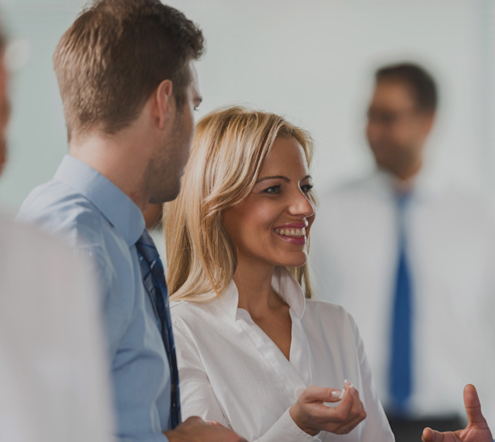 group of smiling people standing and talking