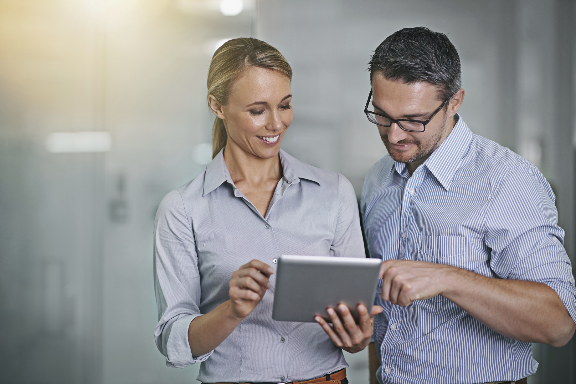 A businessman and a businesswoman look at a tablet device together
