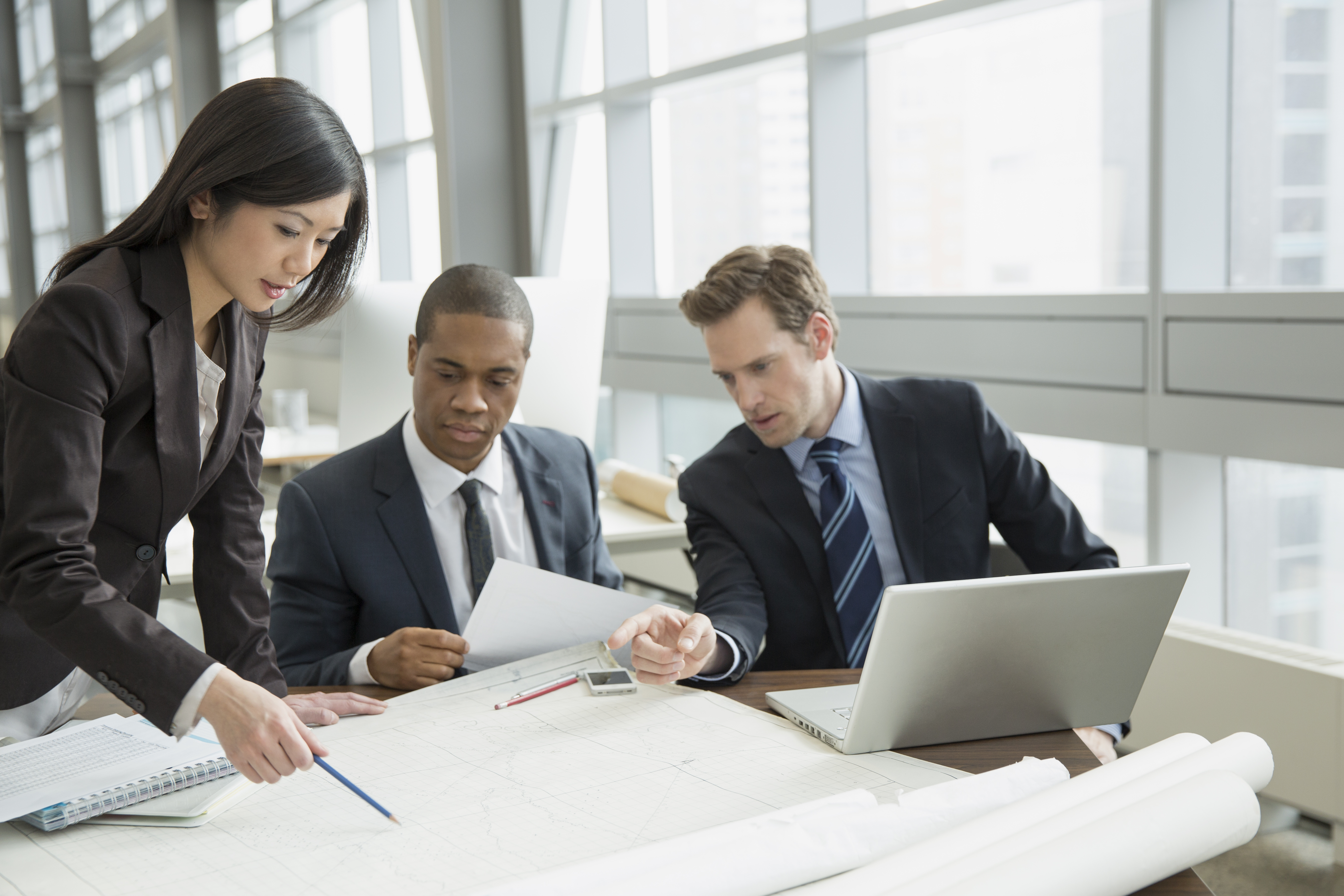 Business people reviewing blueprints at desk