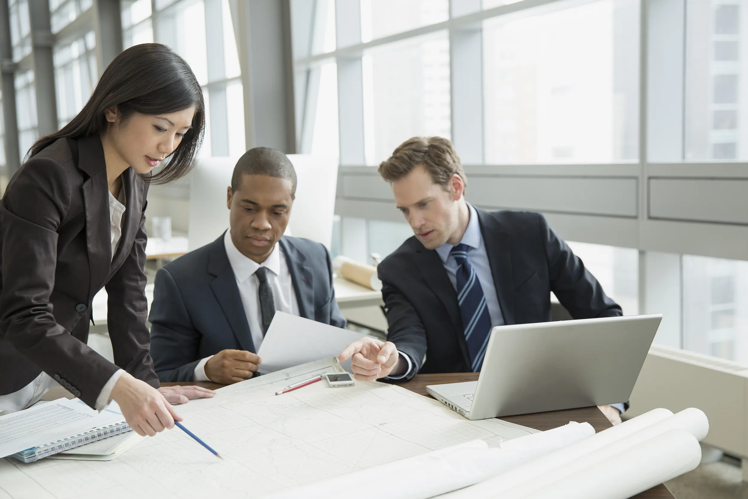 Business people reviewing blueprints at desk