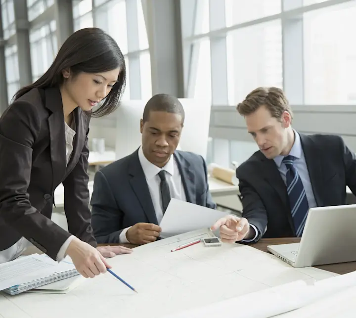 Business people reviewing blueprints at desk