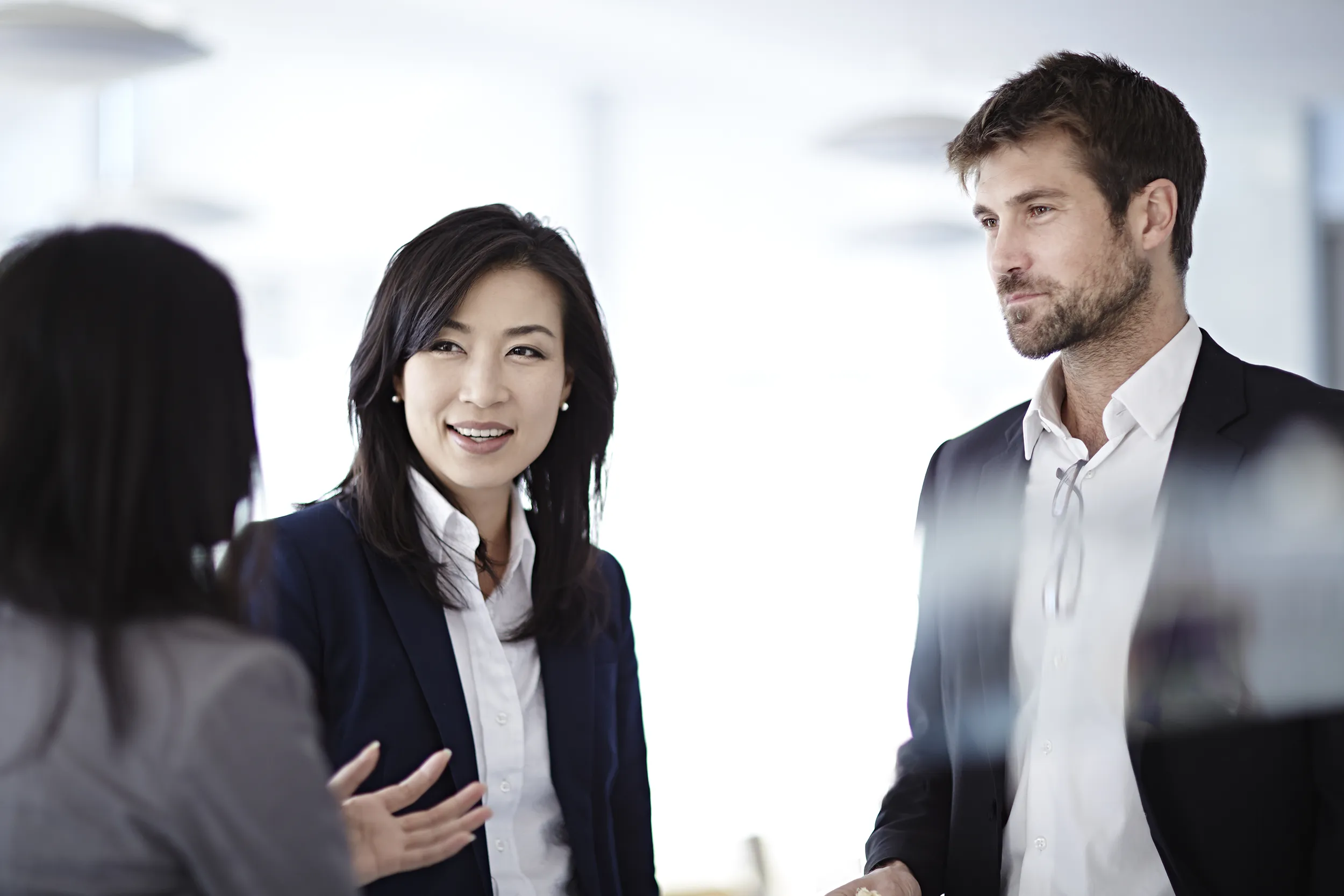 A businesswoman smiling standing next to a businessman