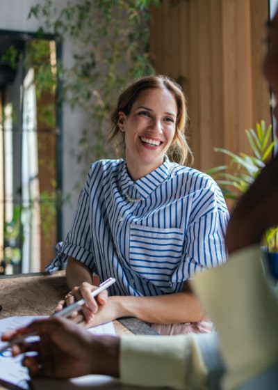 Female corporate secretary smiling at colleague in meeting